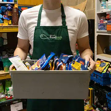 Volunteer holding a box of assorted food items at Longridge Food Bank.